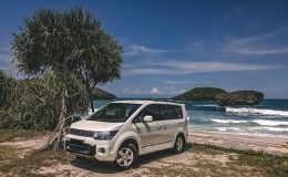 Voiture de location garée face à une plage tropicale