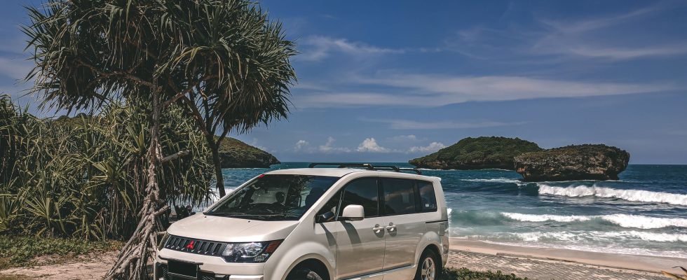 Voiture de location garée face à une plage tropicale